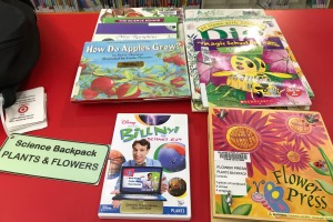 Books, DVD, and flower press activiy on a table with a green tag that says plants and flowers